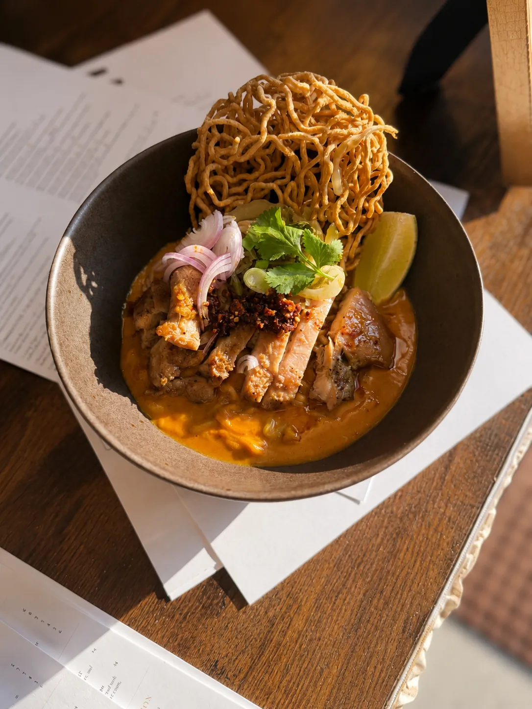 Khao soi curry noodles with grilled chicken, crispy noodles and lime
