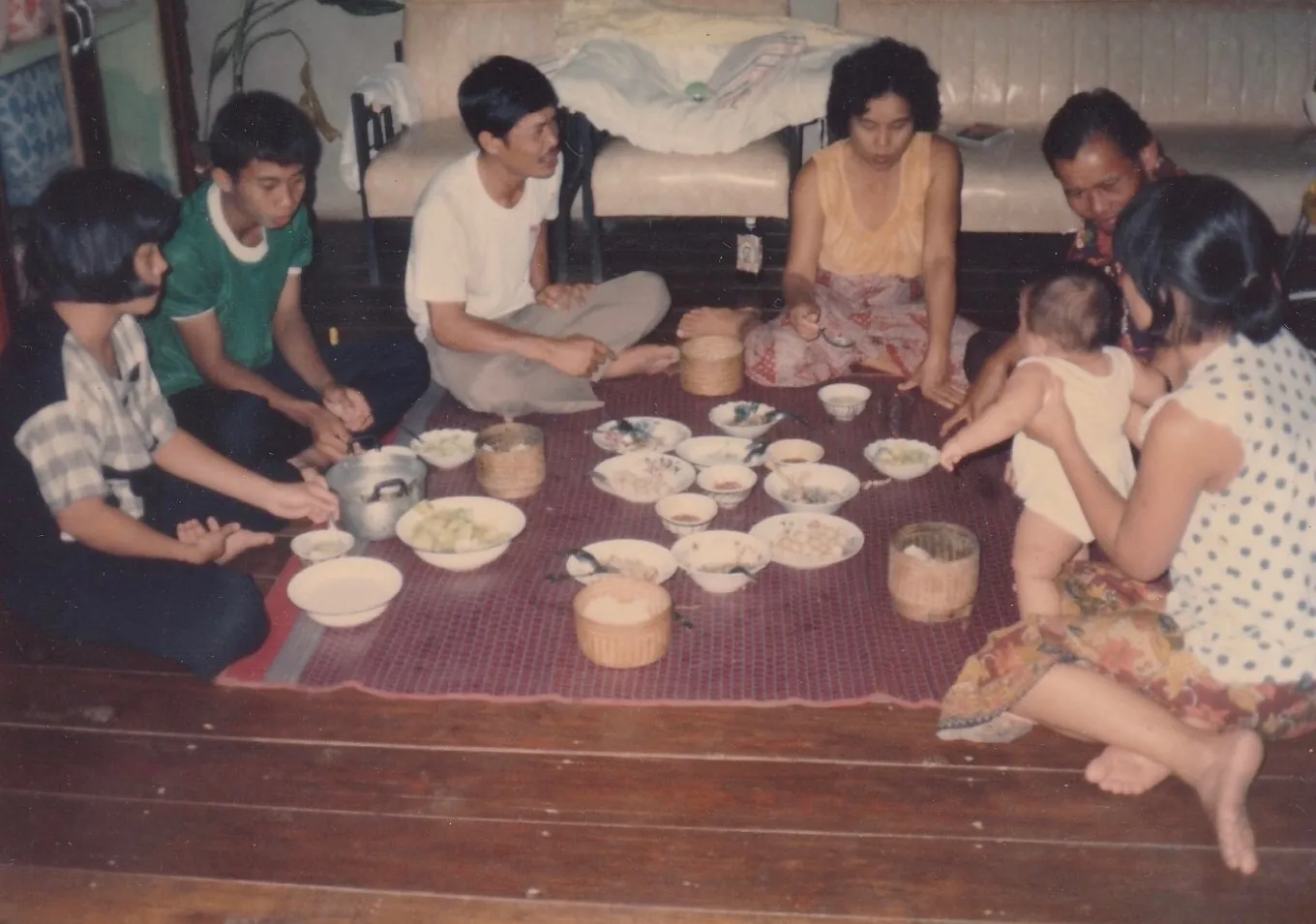 An old family photograph of a meal shared on the floor